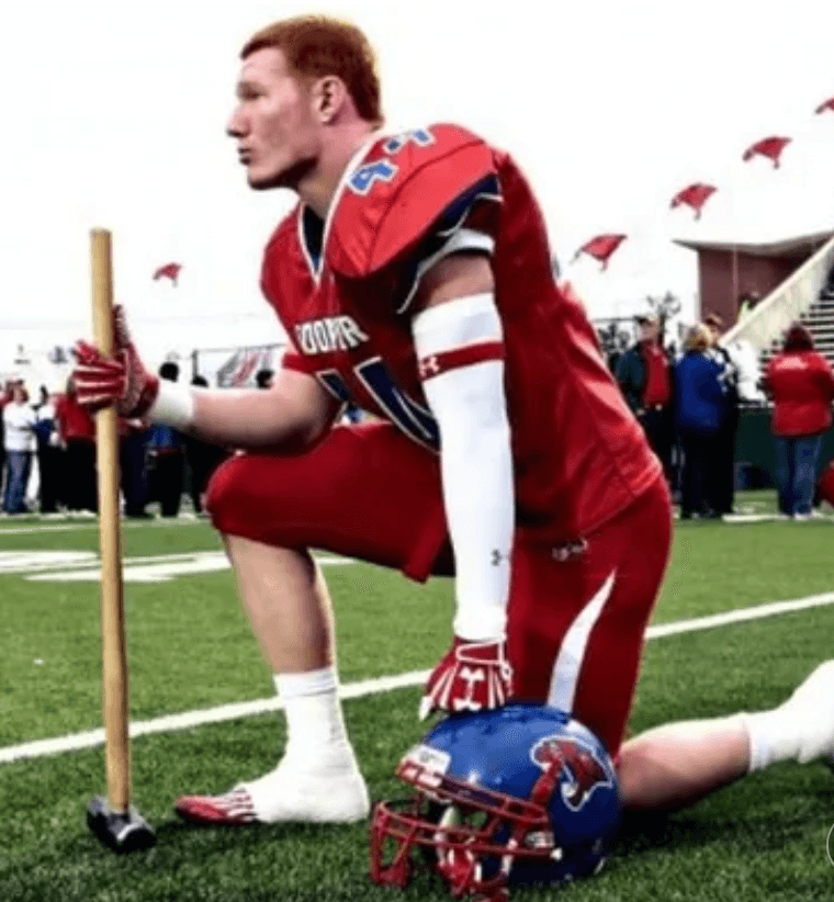 Kaleb Cory kneeling on the football field beside his helmet